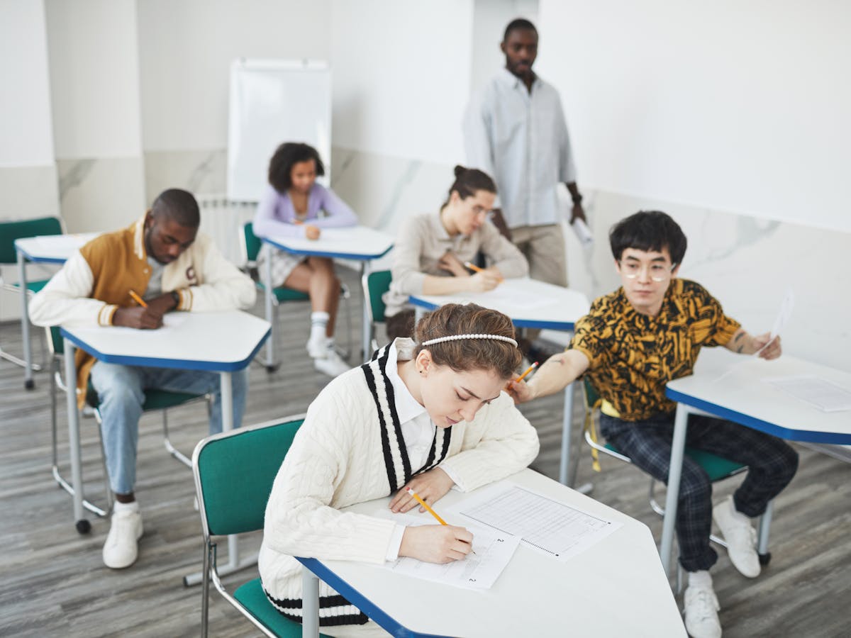 Students from different backgrounds taking an exam in a classroom.